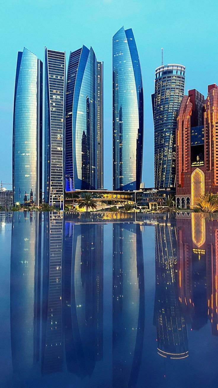 Illuminated Abu Dhabi skyline reflected in water at night