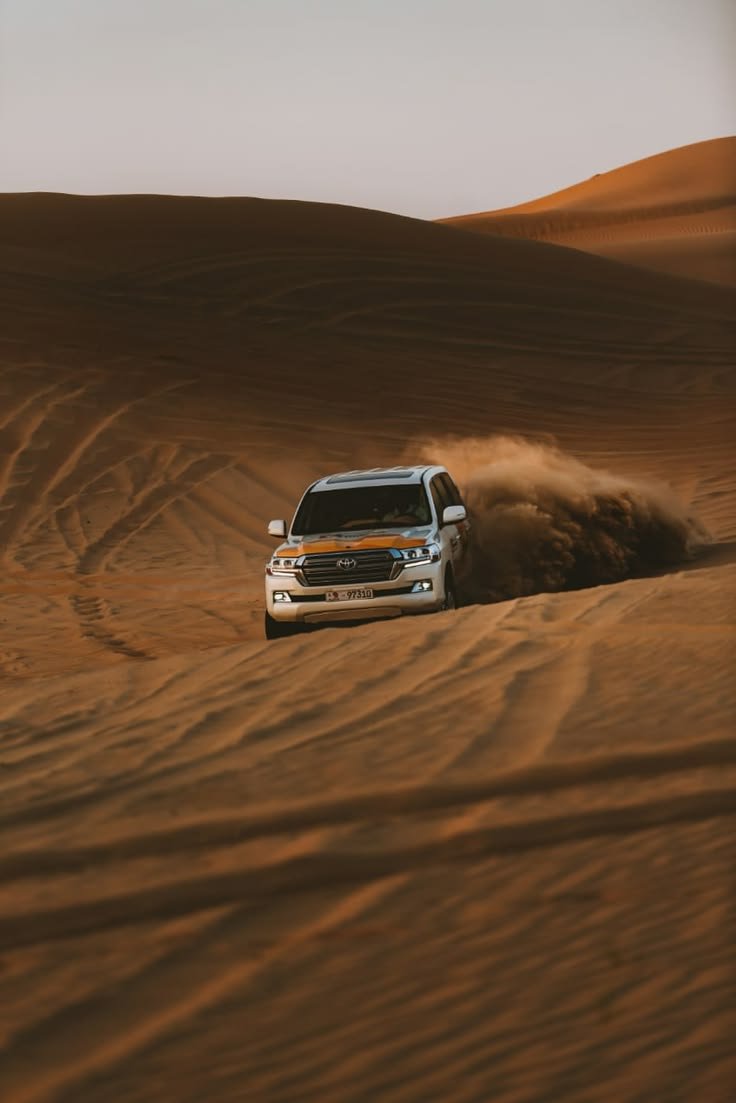 4x4 vehicle driving across the desert dunes