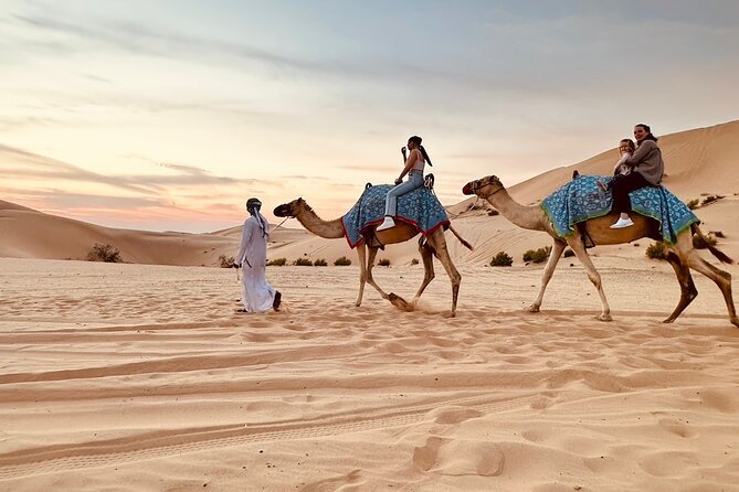 Family on a camel ride at sunset on the desert dunes