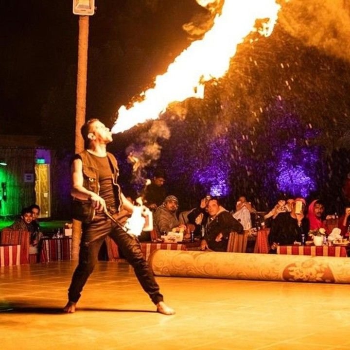 Fire performer breathing fire at the desert safari camp at night