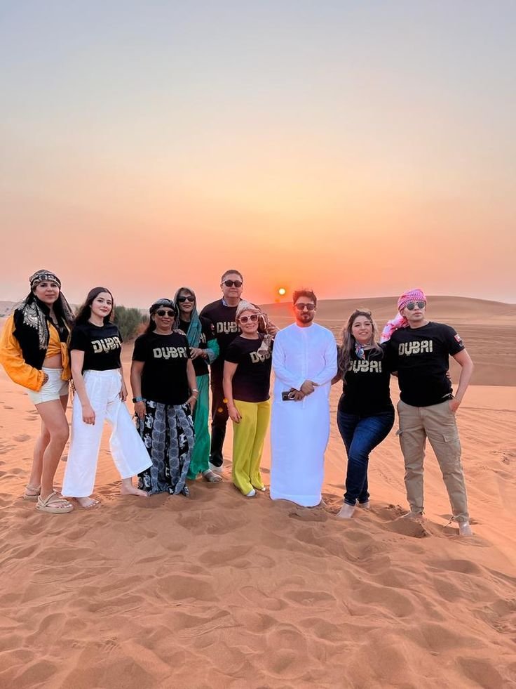 Tour group in Dubai t-shirts posing at sunset in the desert