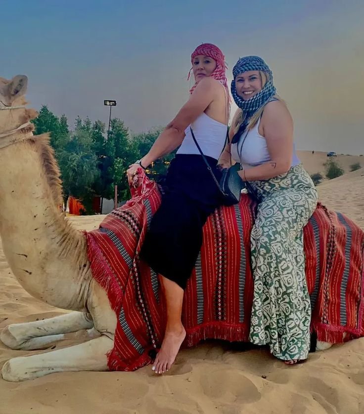 Two women sitting on a camel at the desert safari camp