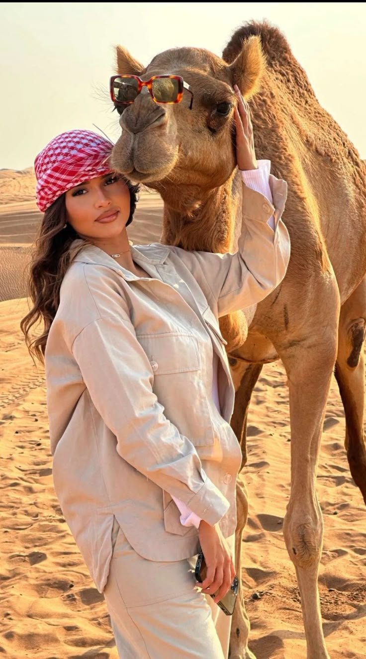 Woman posing with a friendly camel in the desert